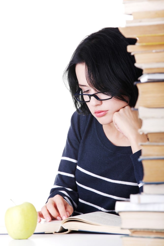 girl studying near tall stack of books