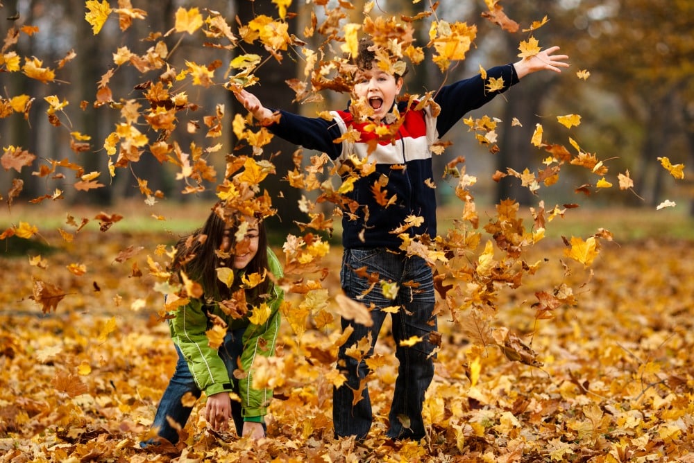 Children throwing fall leaves