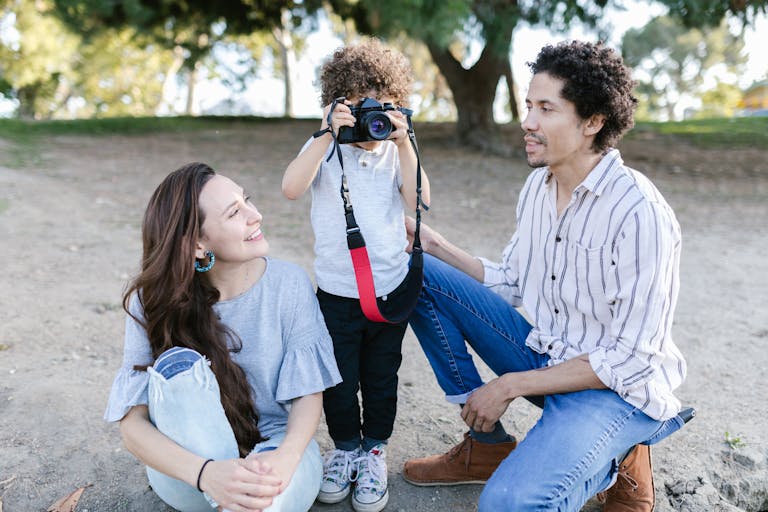 Photo of a Kid Using a Camera Near His Parents